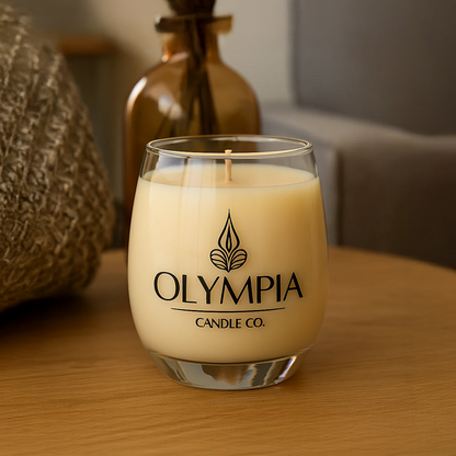 Glass candle with 'Olympia Candle Co.' logo on a wooden surface