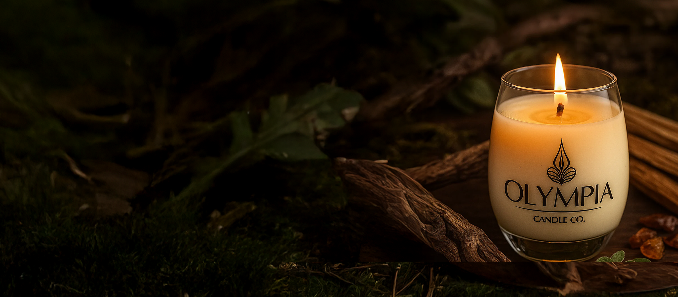 Olympia Candle Co. candle in a glass jar with cinnamon sticks and leaves on a dark background