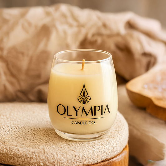 Glass candle with 'Olympia Candle Co.' branding on a textured surface.