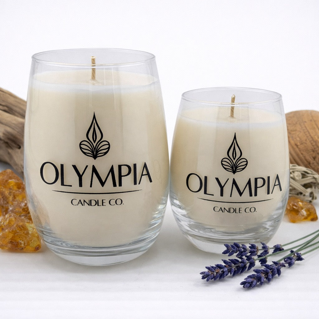 Two glass candles with 'Olympia Candle Co.' logo on a white background with lavender and amber stones.