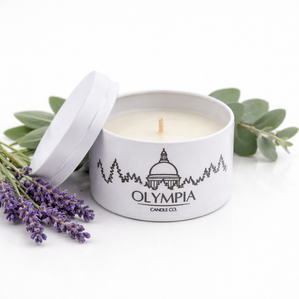 Olympia Candle Co. candle in a tin with lavender and eucalyptus leaves on a white background