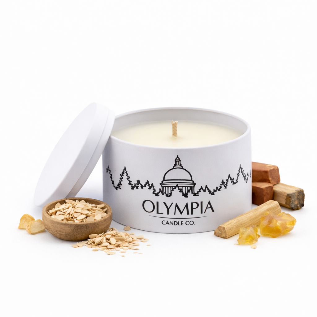 Candle in a white container with 'Olympia Candle Co' branding, surrounded by wooden elements on a white background.