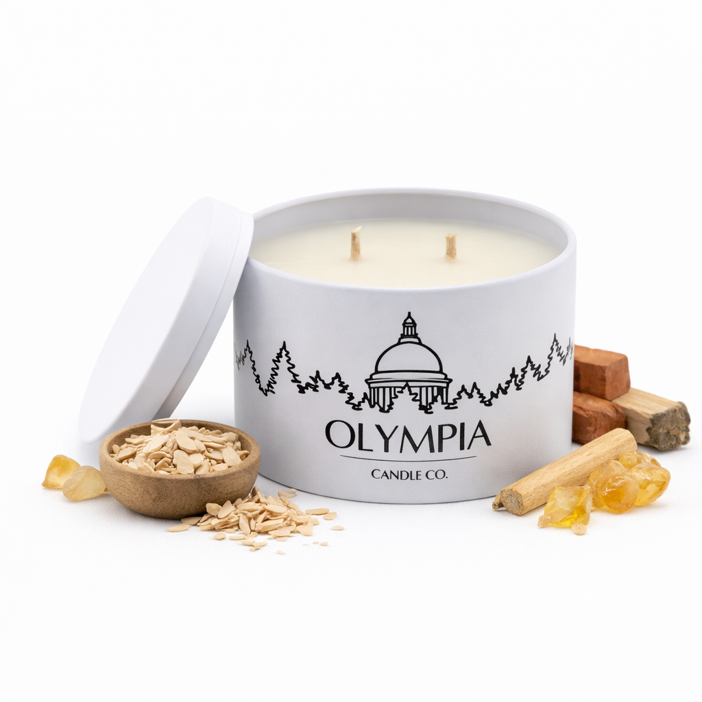 Candle in a white container with 'Olympia Candle Co' branding, surrounded by wooden elements on a white background.