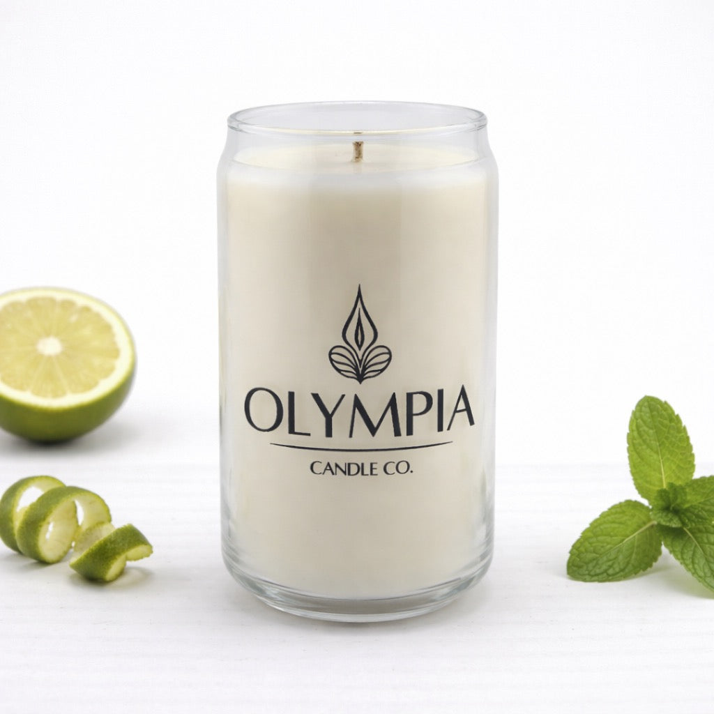 Candle from Olympia Candle Co. with bergamot and mint leaves on a white background