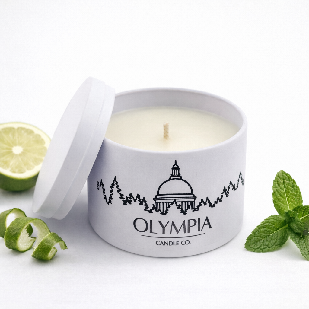 Candle in a white container with 'Olympia Candle Co.' branding, surrounded by mint leaves and a bergamot wedge on a white background.
